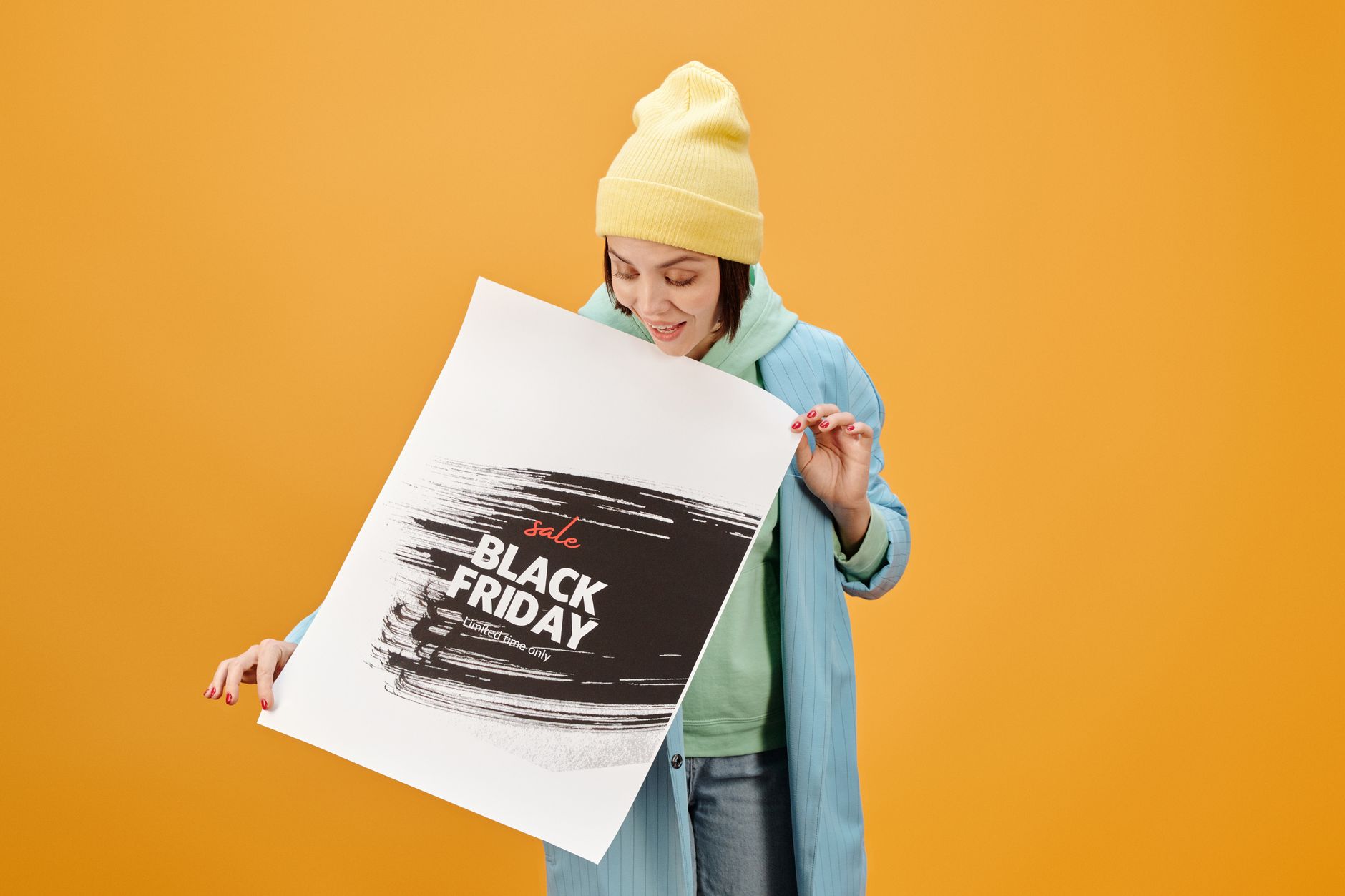 Femme en tenue décontractée tenant une affiche de soldes Black Friday sur un fond jaune.